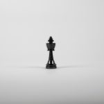 A minimalist black chess king piece on a white background, representing strategy and power.