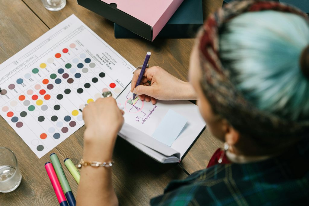 A person working on a color chart and sketchbook in a creative workspace.